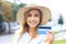 Cheerful young optimistic girl standing outdoors, holding credit card in hand
