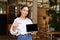 Cheerful young restaurant administrator, asian girl shows digital tablet and smiling