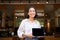 Cheerful young restaurant administrator, asian girl shows digital tablet and smiling