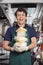 Cheerful Young Salesman Carrying Cheese In Store