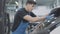 Cheerful young service man dancing as cleaning windshield of vehicle in repair shop. Portrait of joyful brunette