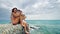 Cheerful young teens sitting by ocean at pier on summer holiday