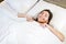 Cheerful young woman in bed with white clean sheets smiling and covering herself with blanket. comfy mattress