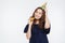 Cheerful young woman in birthday hat with party whistle