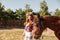 Cheerful young woman cowgirl walking wit her horse on ranch