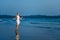 Cheerful young woman dancing on the wet sand, making gestures on the background of the gulf warm summer evening. Carefree holiday