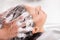 Cheerful young woman has her hair washed in beauty