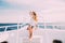 Cheerful young woman leaning at the handrail and smiling at camera while standing on the ship`s bow