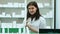 A cheerful young woman pharmacist with a bottle of drugs standing in pharmacy drugstore looking at camera