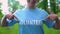 Cheerful young woman pointing at volunteer word on t-shirt, responsibility