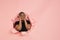 Cheerful young woman poses in torn coral paper hole background, emotional and expressive