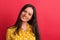 A cheerful young woman in studio on a red background.