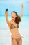 Cheerful young woman taking self photo on beach