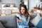 Cheerful young woman using mobile phone while sitting on a couch at home