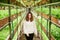 Cheerful young woman walking down greenhouse.