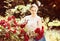 Cheerful young woman working with bush roses with horticultural