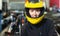 Cheerful young woman in yellow helmet at kart circuit