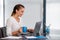 Cheerfull young business woman sitting at her desk and drinking tea.