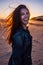 Cheerfull young woman on a sunset on the beach. Staring at camera