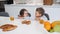 Cheerfulness. Pretty inspired little dark-haired girl smiling and looking at her brother while they having breakfast