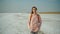 Cheerfulness woman in cozy sweater with orange backpack on nature landscape of the salt flats, looks like a white desert