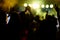 cheering crowd in front of bright yellow stage lights. Silhouette image of people dance in disco night club or concert