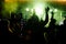 cheering crowd in front of bright yellow stage lights. Silhouette image of people dance in disco night club or concert