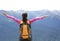Cheering hiking woman open arms on mountain peak
