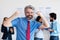 Cheering mature businessman with gray hair and international team in background team