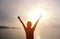 Cheering woman open arms to sunrise at sea