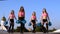 Cheerleader girls with pompoms dance outdoors on sky backround