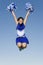 Cheerleader With Pompoms In Midair Against Sky