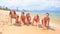 Cheerleaders in bikinis crawl in line along sand beach smile