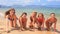 cheerleaders in bikinis crawl in line along sand beach smile