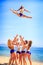 Cheerleaders perform Toe Touch Toss on beach