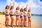 Cheerleaders pose in line hands upwards on beach against sea