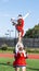 Cheerleaders in pyramid holing teammate overhead