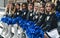 Cheerleaders sitting on chairs in a row dressed in mini-skirts holding pom-poms