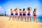 Cheerleaders stand backside view on beach against azure sea