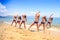 Cheerleaders stand in triangle hands over head on wet sand