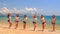 Cheerleaders in uniform step out of water stand in line on beach