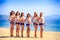 Cheerleaders in white blue stand in line on beach against sea