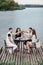 Cheers! Group of friends enjoying outdoor picnic in river pier