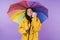 Cheery brunette woman in yellow raincoat holding umbrella