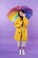 Cheery brunette woman in yellow raincoat holding umbrella