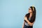 Cheery Indian teen girl pointing aside at blank space on blue studio background