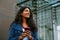 Cheery woman using mobile phone while walking through city street