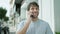 Cheery young man speaking on phone, flashing his smile on a casual street stroll