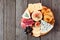 Cheese board with a selection of cheeses and meats, top view on a wooden background