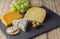 Cheese board with three cheeses, gouda with pimento, gouda with cumin seeds and roquefort blue cheese close up on rustic wooden